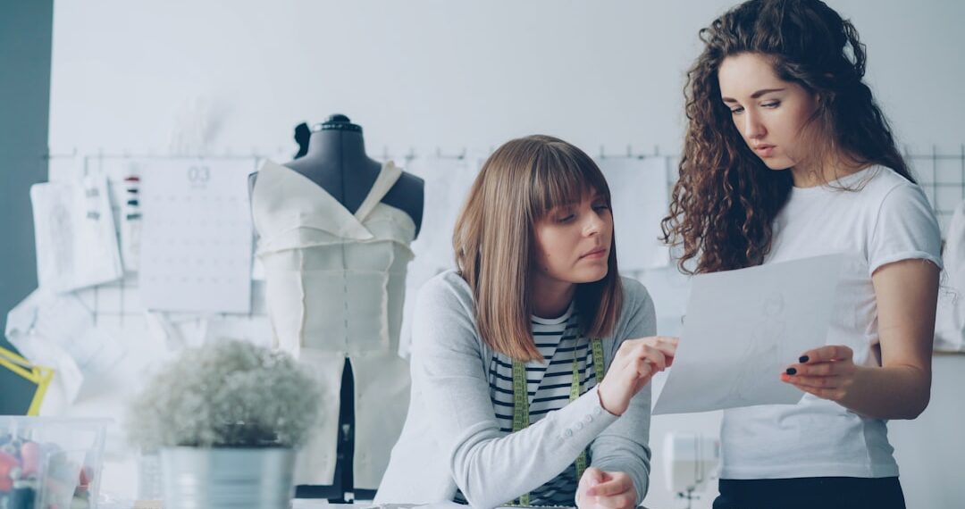 Professional female fashion designers are looking at sketch and discussing details of future clothes. Productive cooperation and creating new clothing collection concept.