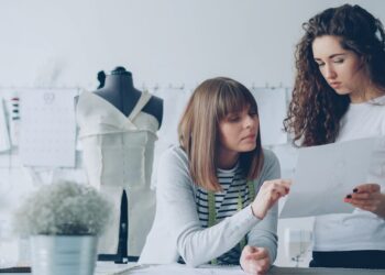 Professional female fashion designers are looking at sketch and discussing details of future clothes. Productive cooperation and creating new clothing collection concept.