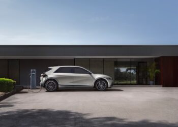 The right side view of the Hyundai IONIQ 5 charging in front of a building.